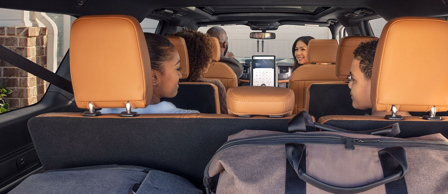 Family in SUV, smiling, with luggage in rear cargo area